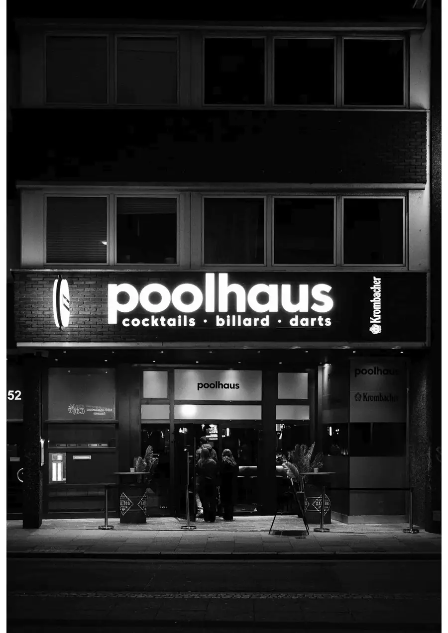 Der beleuchtete Eingang des Poolhauses bei Nacht